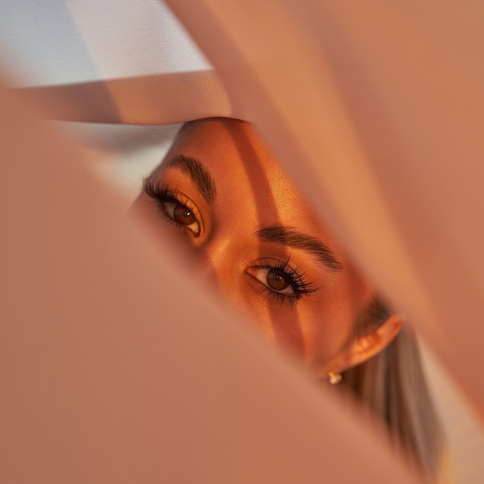 Close-up beauty portrait with warm golden-hour light and soft draped fabric